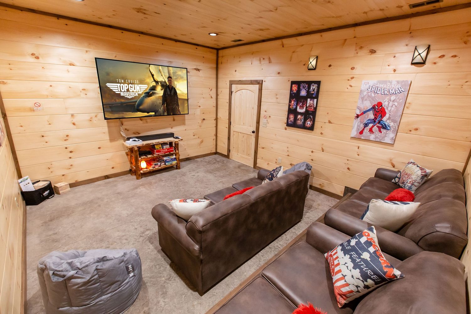 Spacious game room with comfortable seating and entertainment setup against wooden walls.