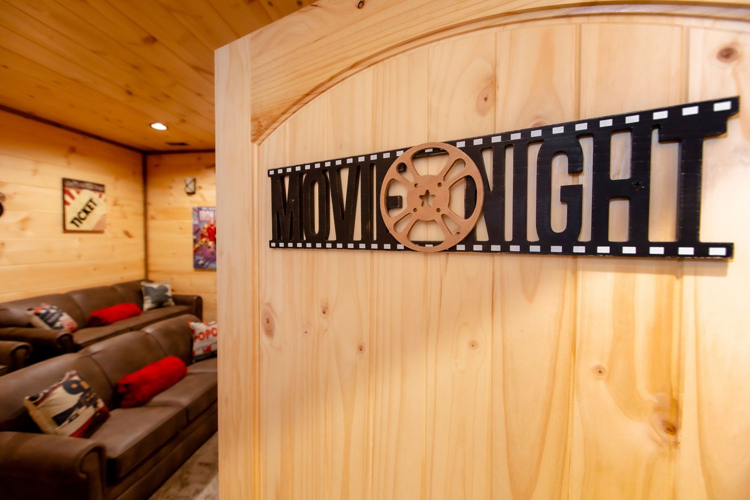 A cozy wooden sauna interior with pine walls, benches, and decorative movie reel artwork mounted on the wall.