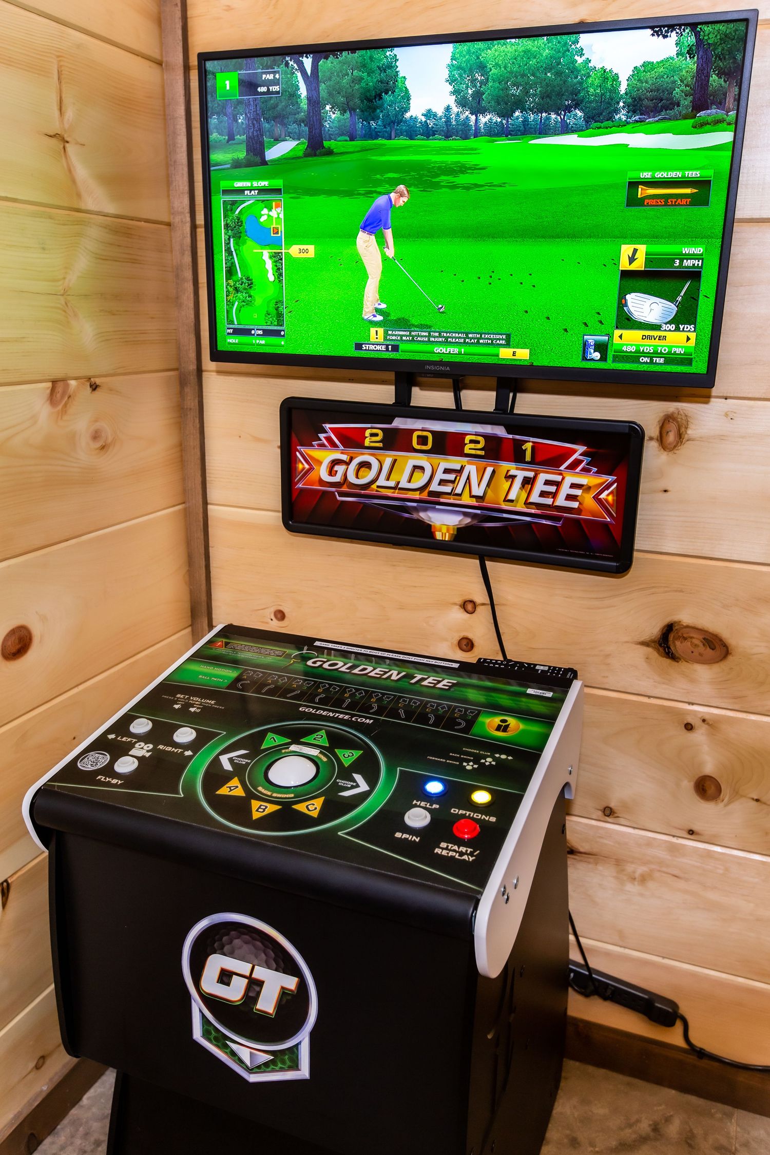Modern golf simulator arcade setup with multiple screens and gaming consoles in a wood-paneled room.