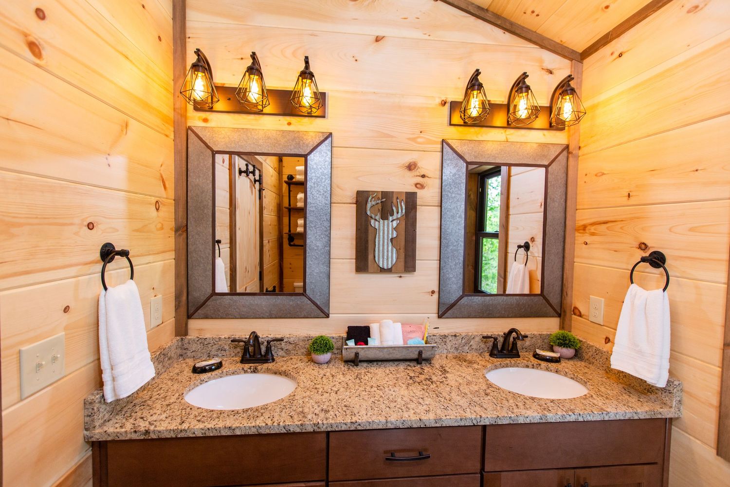 Modern bathroom interior with wood paneled walls, granite countertops, and pendant lighting fixtures.