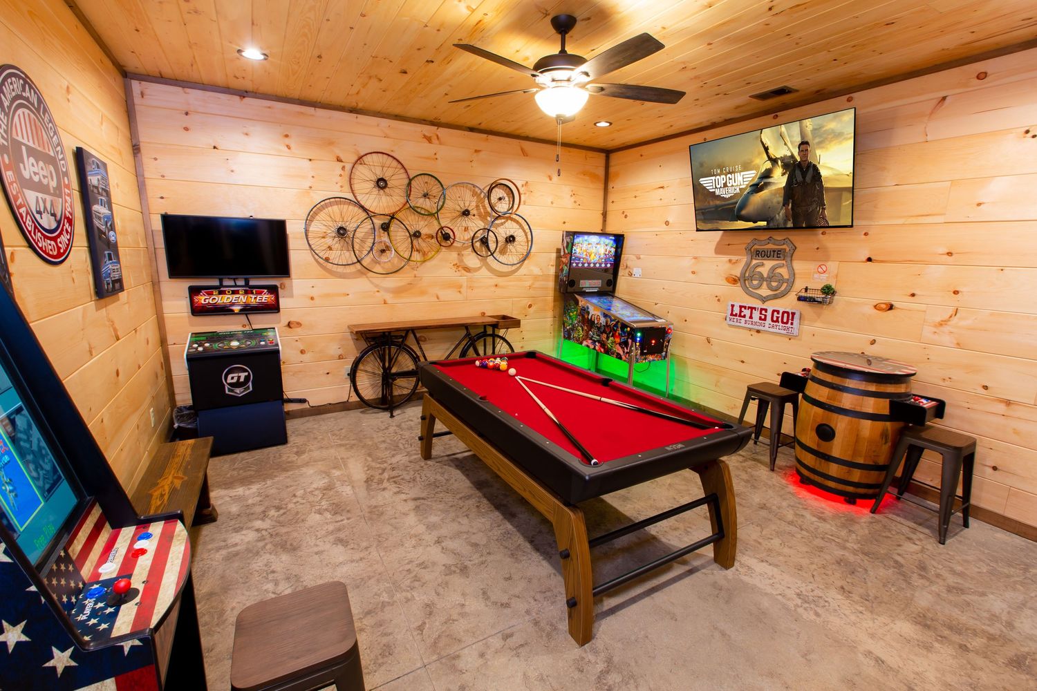 Spacious game room with wood ceiling, pool table, and entertainment setup in rustic cabin style.