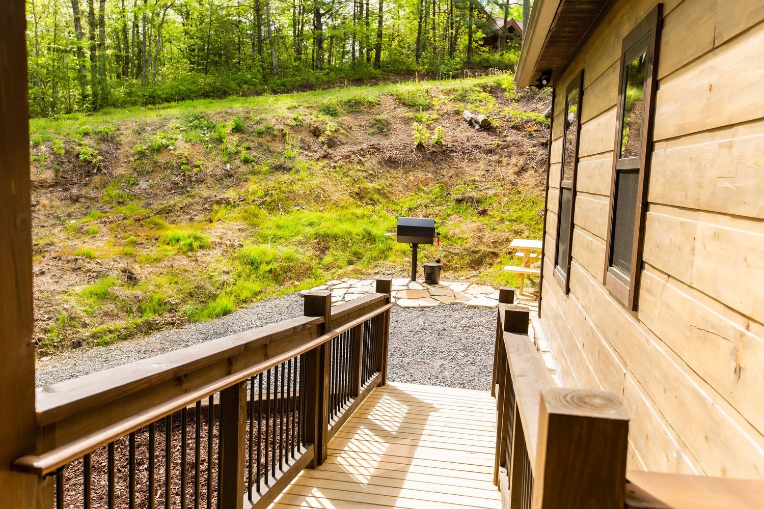 Panoramic view of wooden deck wrapping around a cabin surrounded by lush forest.