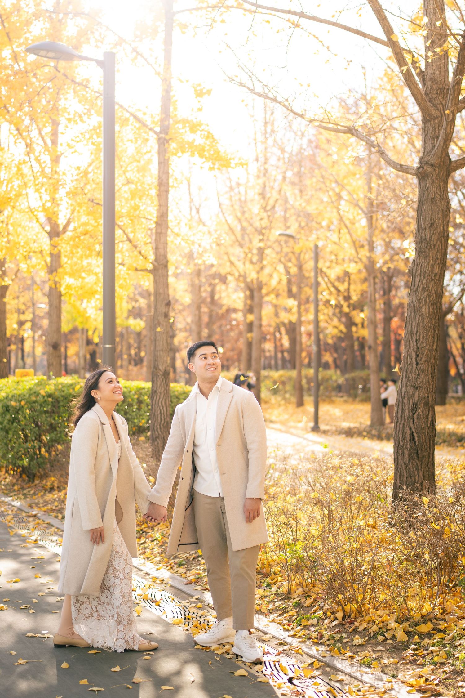 A couple in traditional hanbok clothing dances playfully at a historic Korean palace.