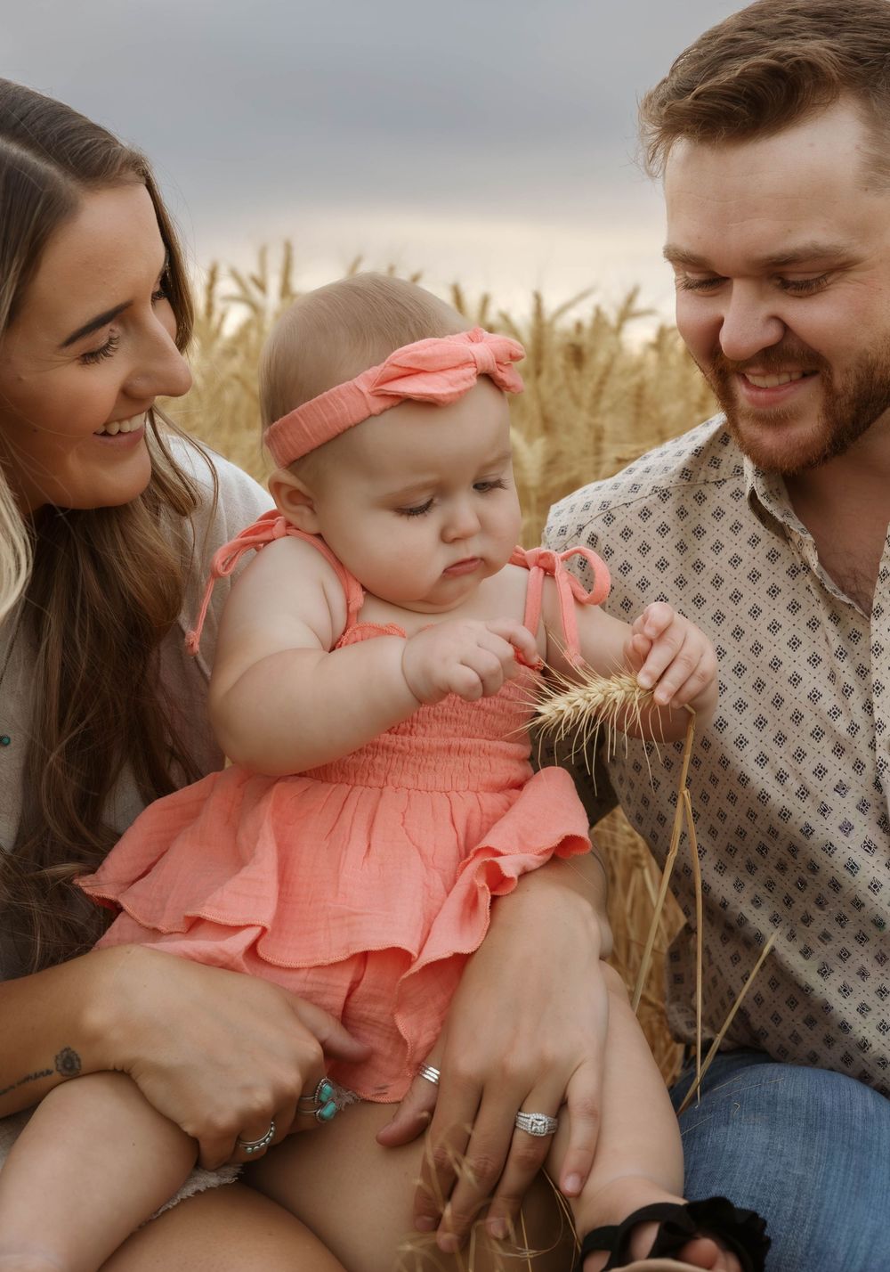 A family shares joyful moments together in a wheat field at sunset.