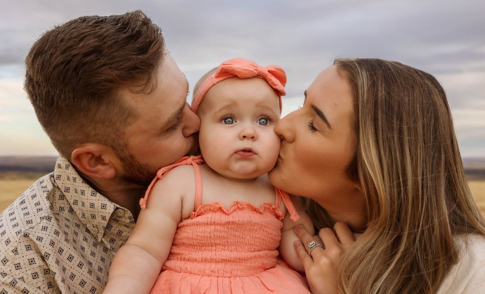 A loving family shares tender moments in a wheat field during golden hour.