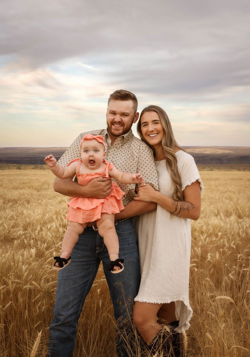 A family plays together in a golden wheat field during sunset.