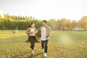 People walking in a grassy field during golden hour sunset.