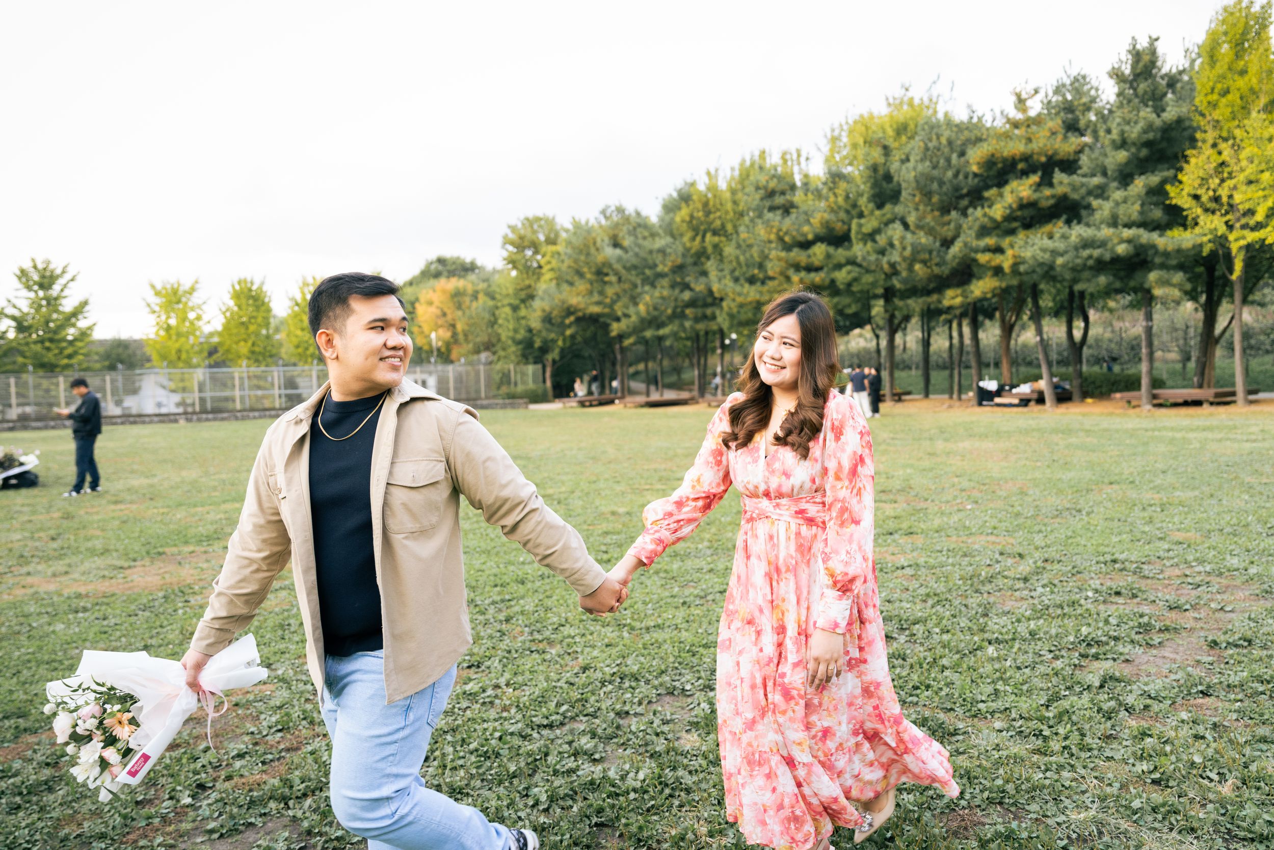 Couple enjoying a playful moment in a sunny field during spring.