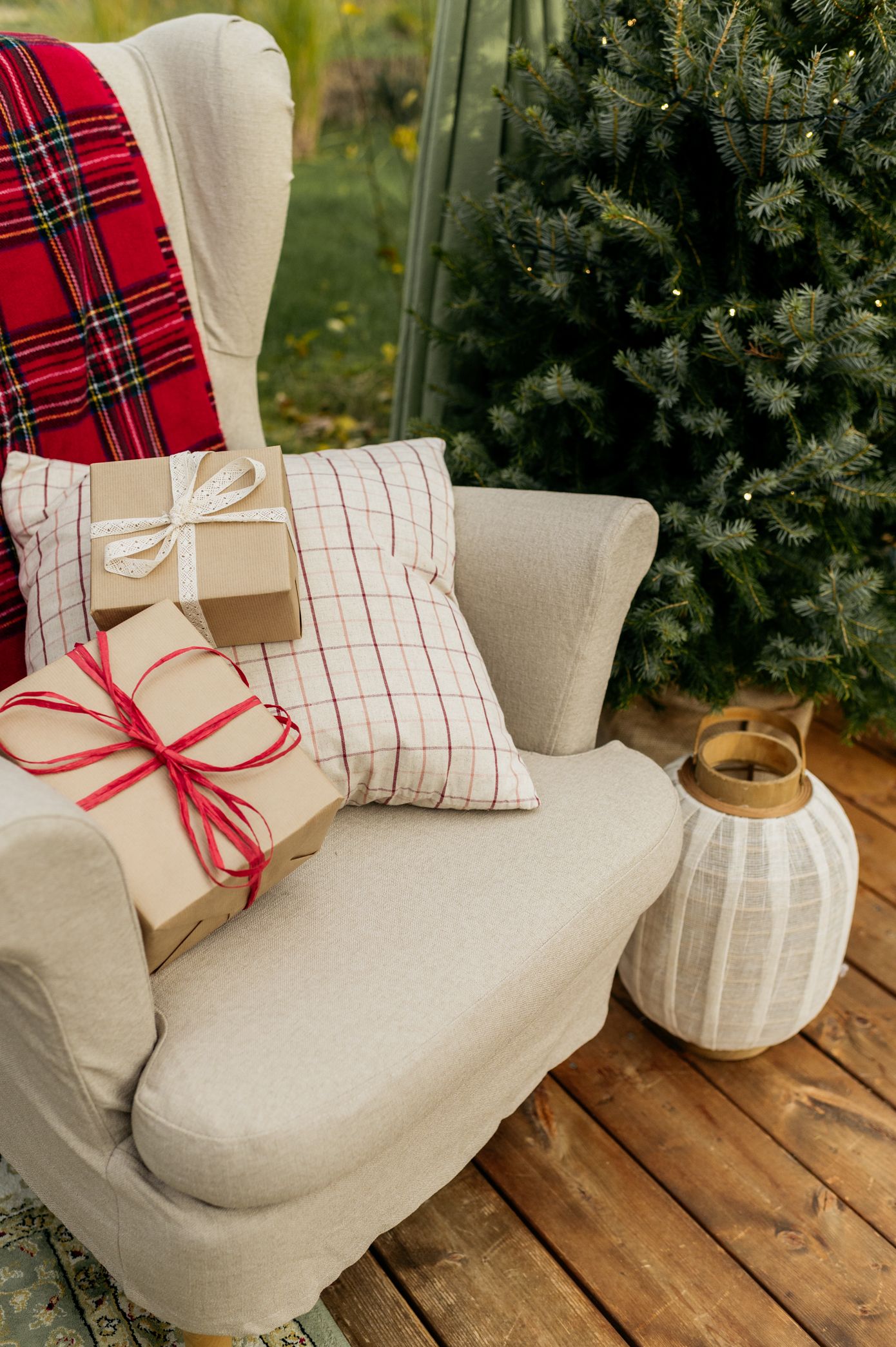 A series of photos showing a cozy beige armchair with plaid throw pillows and wrapped gifts against an evergreen backdrop.