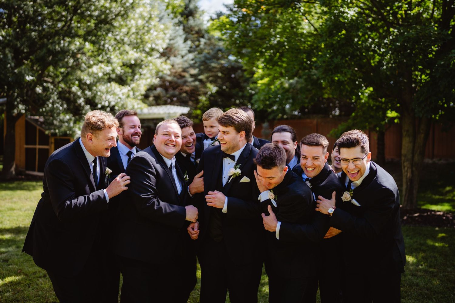 A candid moment captured at an outdoor wedding with guests mingling among lush greenery in a natural setting.