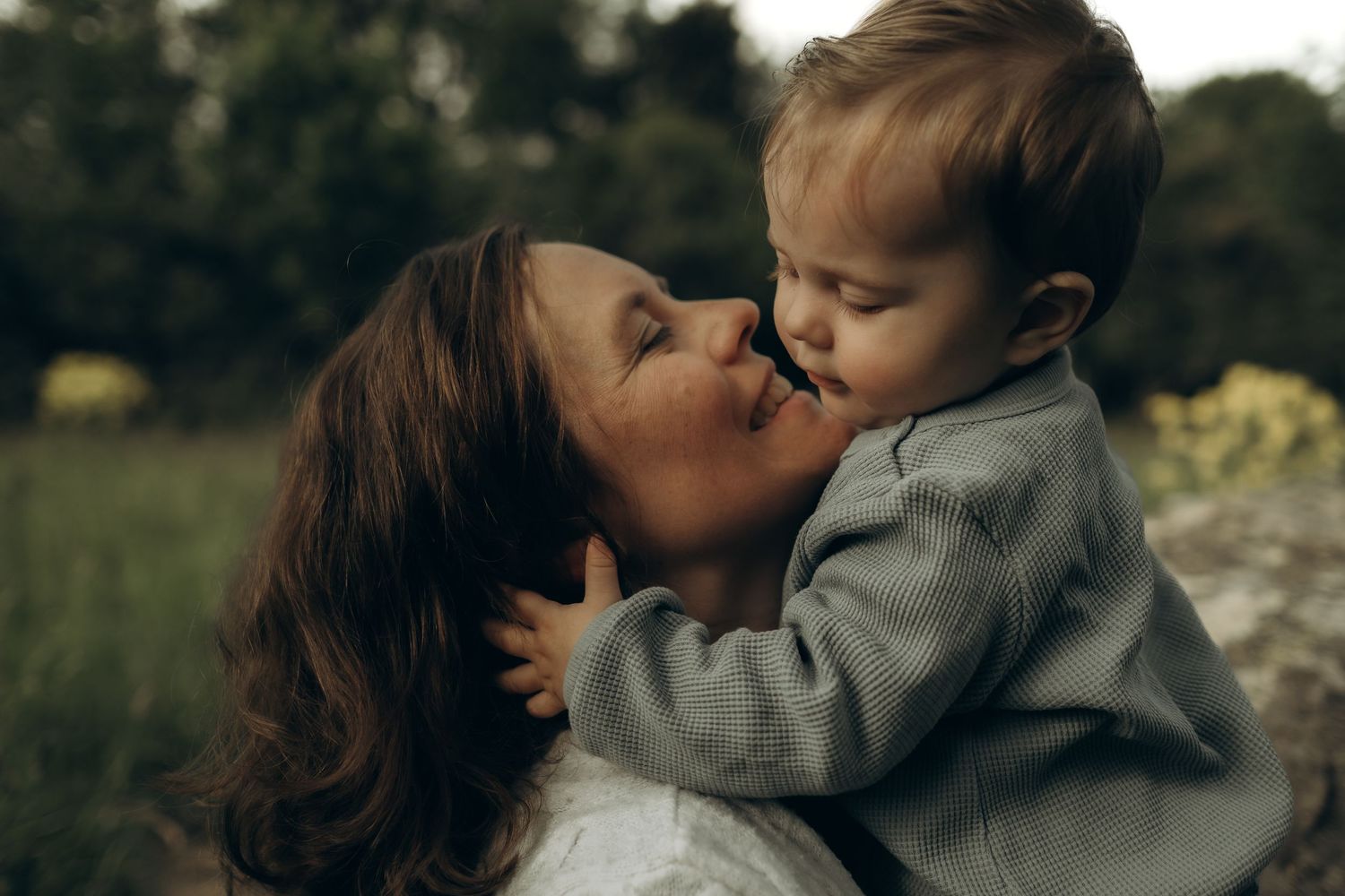 baby son hugging her mother's face while being captured by documentary family photographer in Stockholm