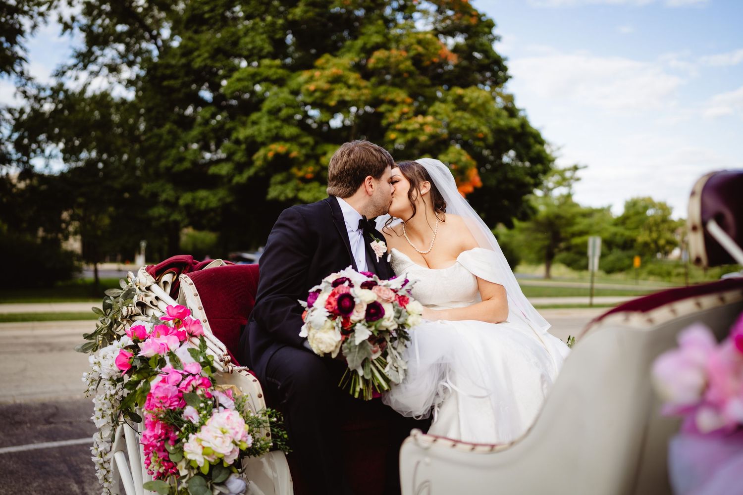 A romantic wedding couple shares tender moments in an outdoor garden setting with vibrant pink floral arrangements.