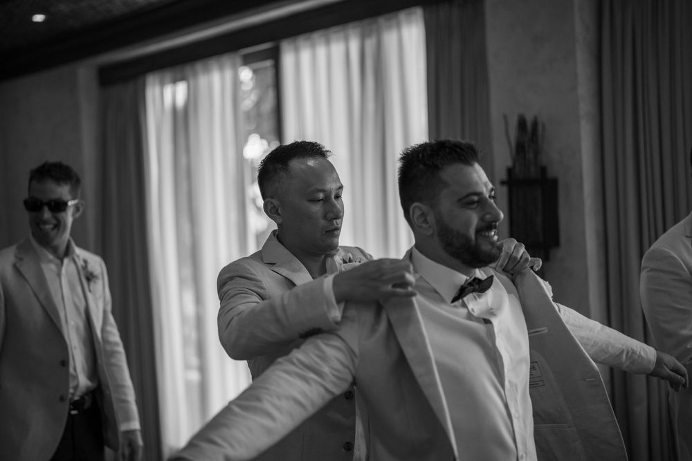 Black and white photo of groomsmen sharing a joyful moment while getting ready.