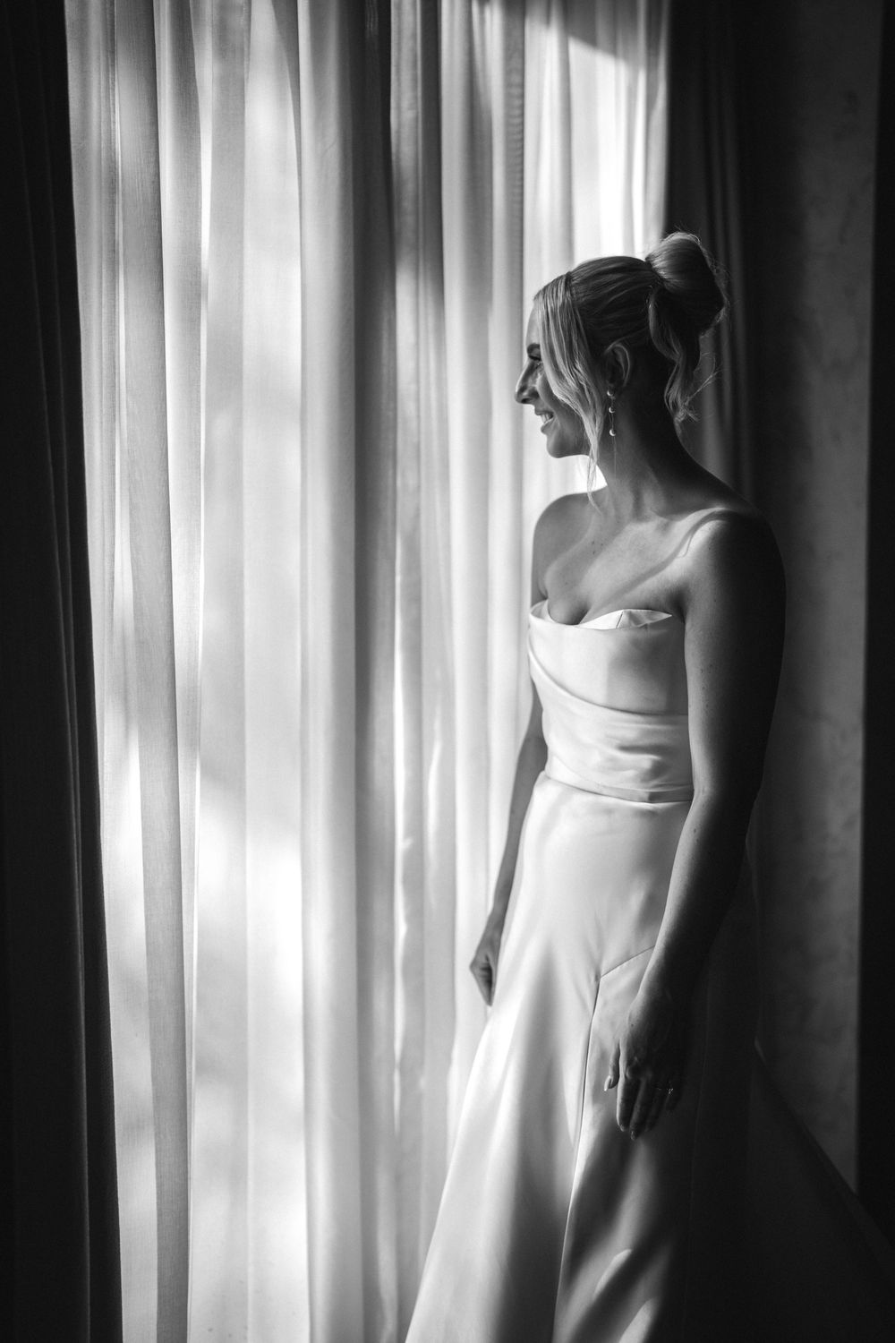 A moody black and white triptych shows a woman in a white dress standing near sheer curtains.