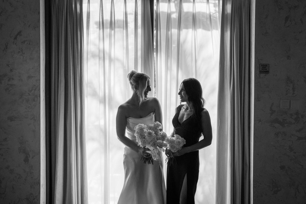 Silhouettes of a couple embrace in front of a bright sunlit window creating an intimate romantic moment.