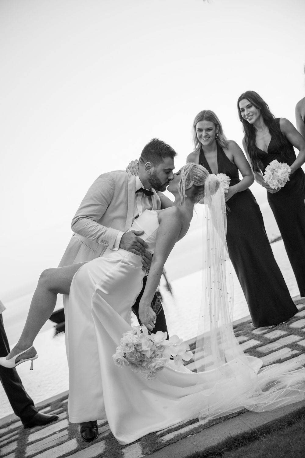 Black and white wedding photo sequence shows a romantic dip kiss between newlyweds on their special day.