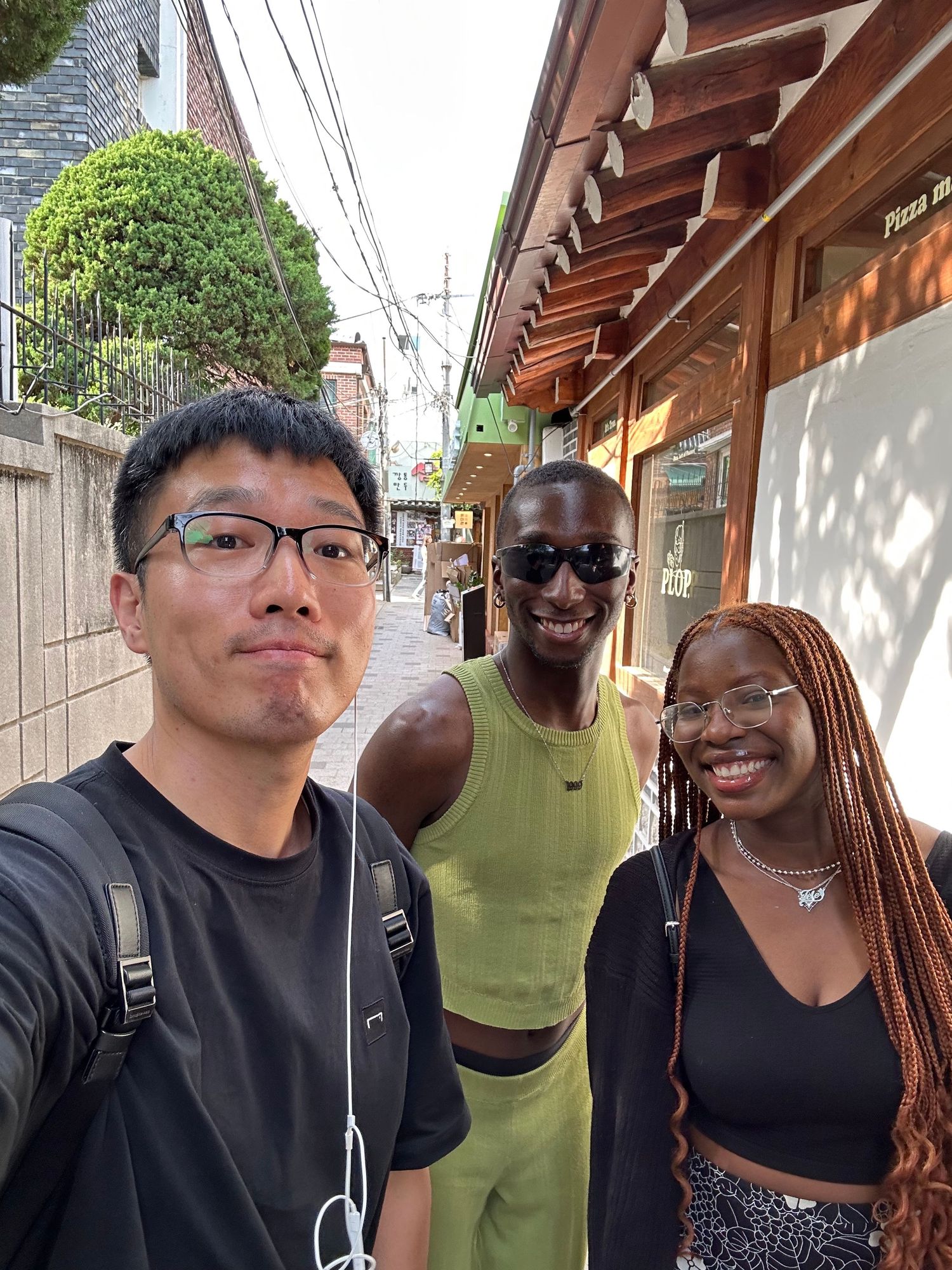 Two friends stand close together smiling at the camera in a series of outdoor selfie photos.