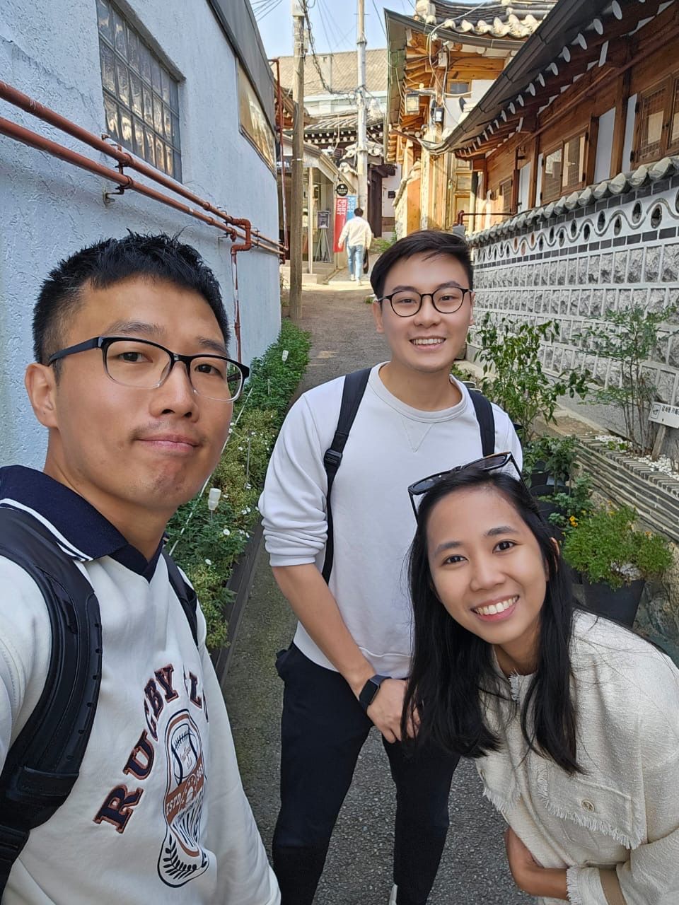Five similar photos showing friends posing together outdoors against traditional Asian architecture and walls.