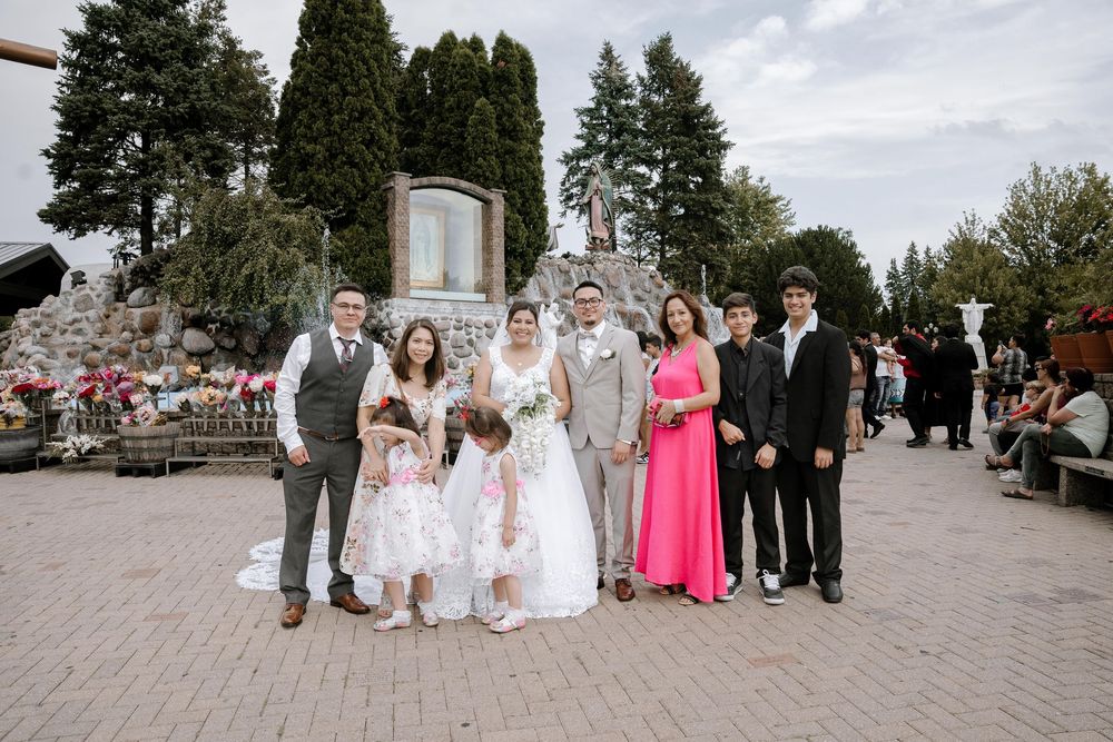 Wedding group photo outdoors with formal attire in shades of pink, blue and beige.