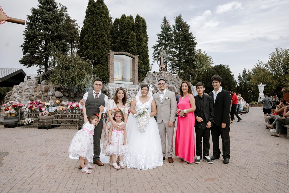 Wedding party poses together outdoors with beautiful floral arrangements and greenery in the background.