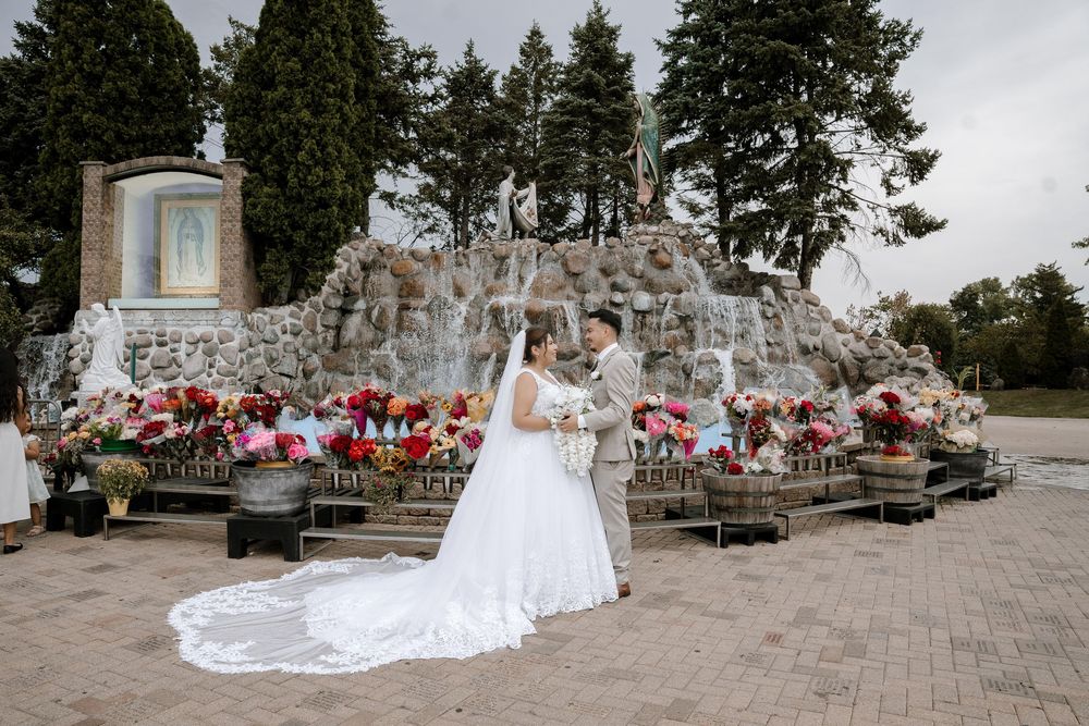 Wedding party gathered for formal photos on outdoor stone patio with evergreen trees.