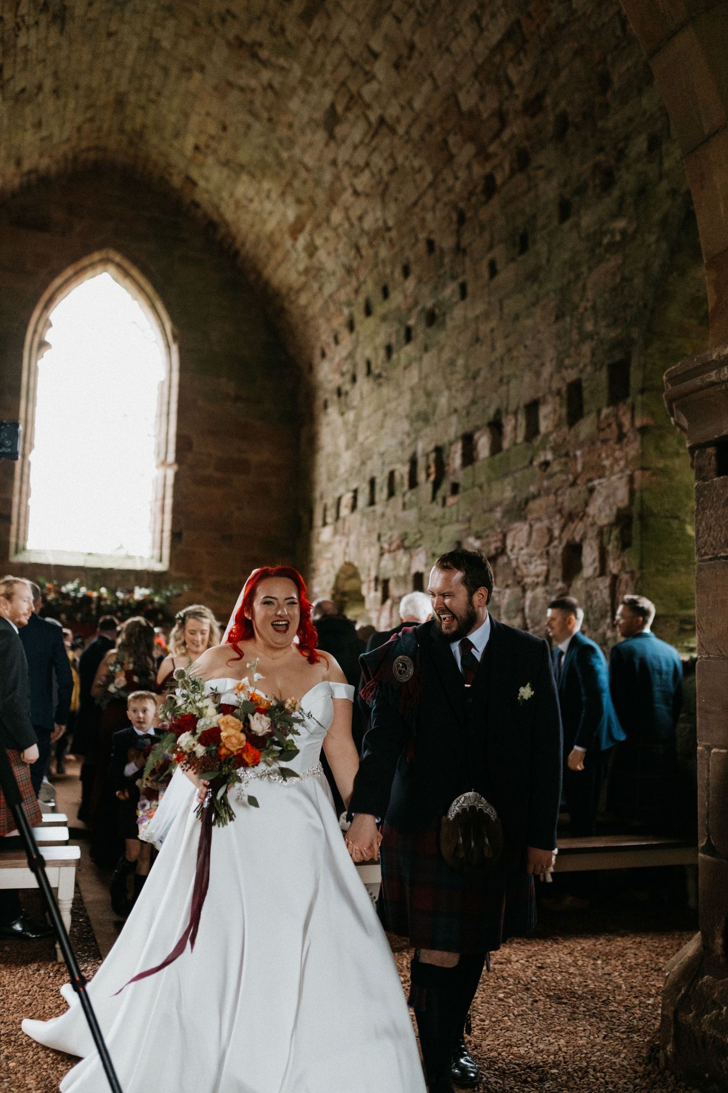 Wedding ceremony in a historic stone church with gothic arched windows.