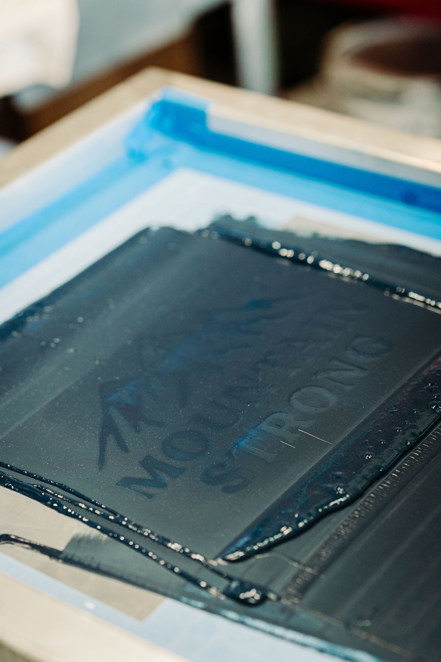 Closeup view of a dark gray photo film strip or negative being developed in a photography darkroom process.
