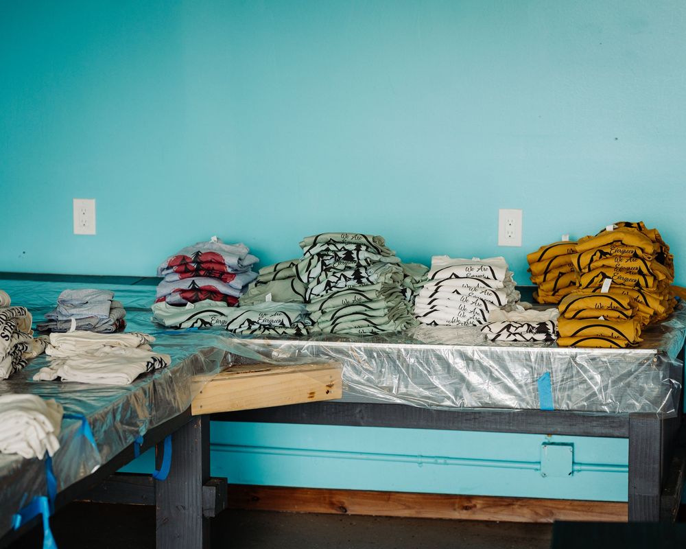 Folded blankets and linens stacked neatly on a wooden bench against a turquoise blue wall.