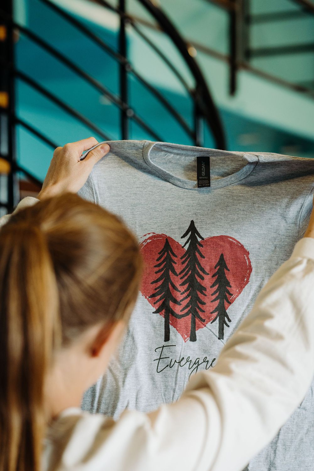 A series of close-up views showing a gray t-shirt with evergreen trees and heart designs printed in coral red.