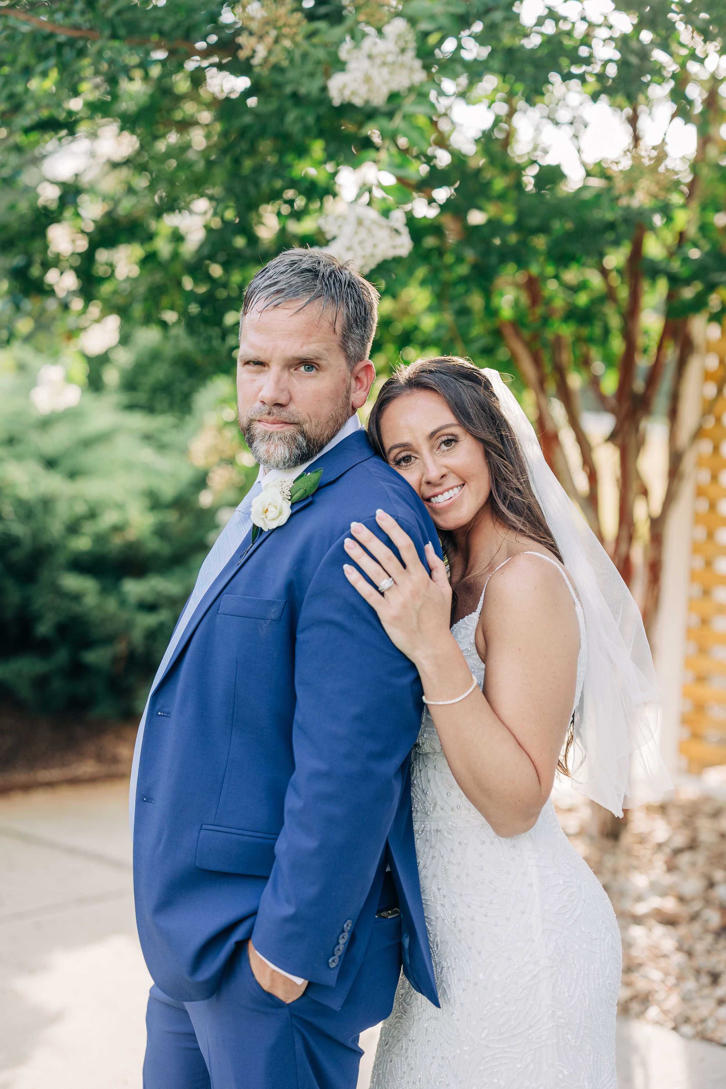 Romantic wedding couple shares tender moments outdoors in summer garden setting with lush greenery.
