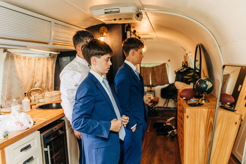 Inside view of luxury RV showing wooden interiors, kitchen amenities and people gathering in the living space.