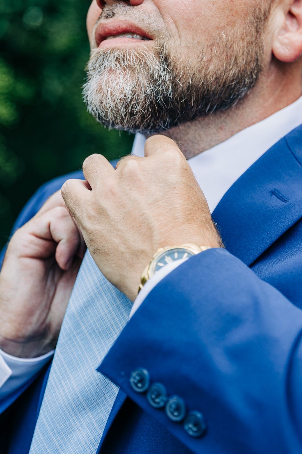 Close-up sequence of man in blue suit adjusting beard and collar with thoughtful expression.