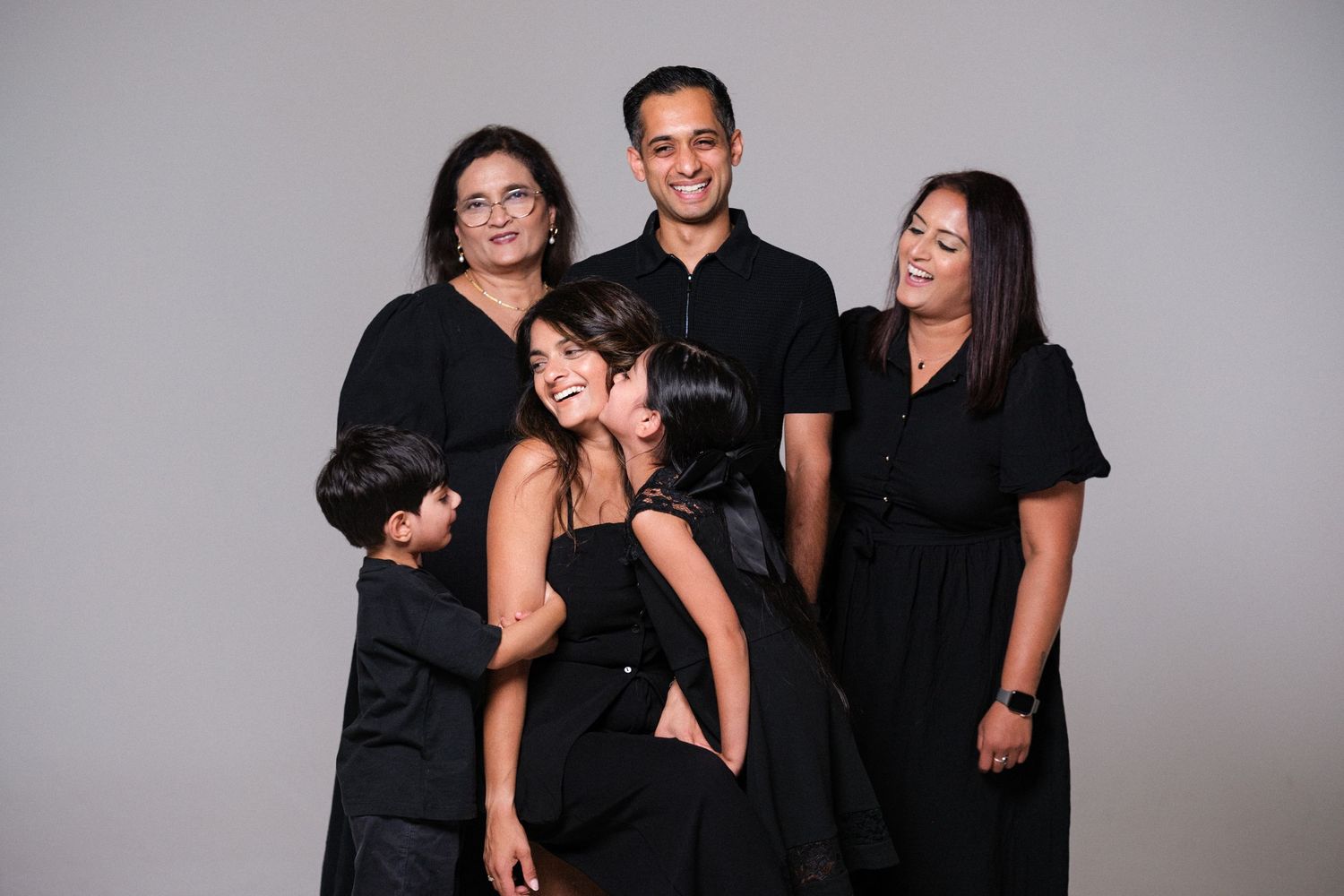 Group photo series showing playful interactions between people wearing black outfits.