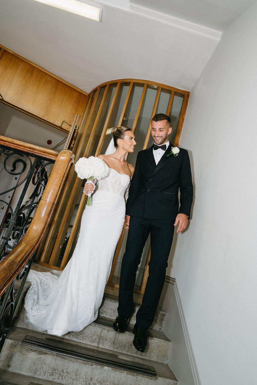 Sequence of wedding photos showing couple in black suit and white dress walking up illuminated indoor staircase.