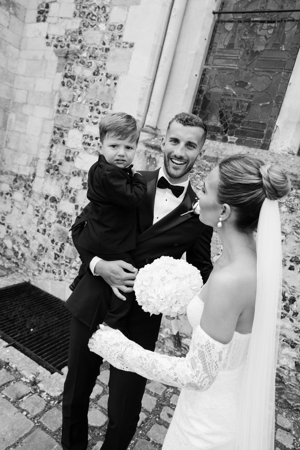 Series of intimate black and white wedding portraits against a stone church wall.