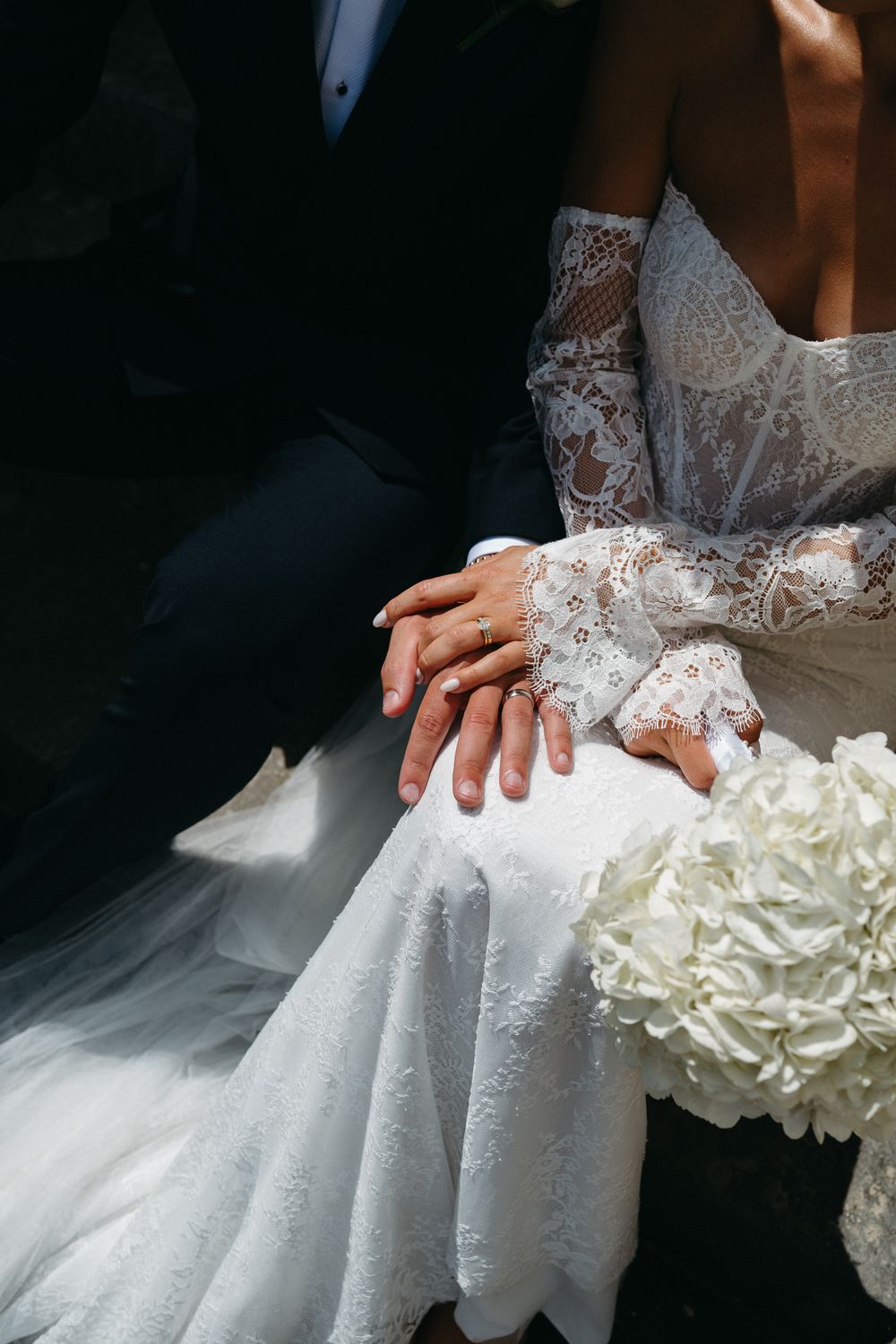 Delicate lace and flowing fabric details of a white wedding dress with layered ruffles create an elegant bridal silhouette.