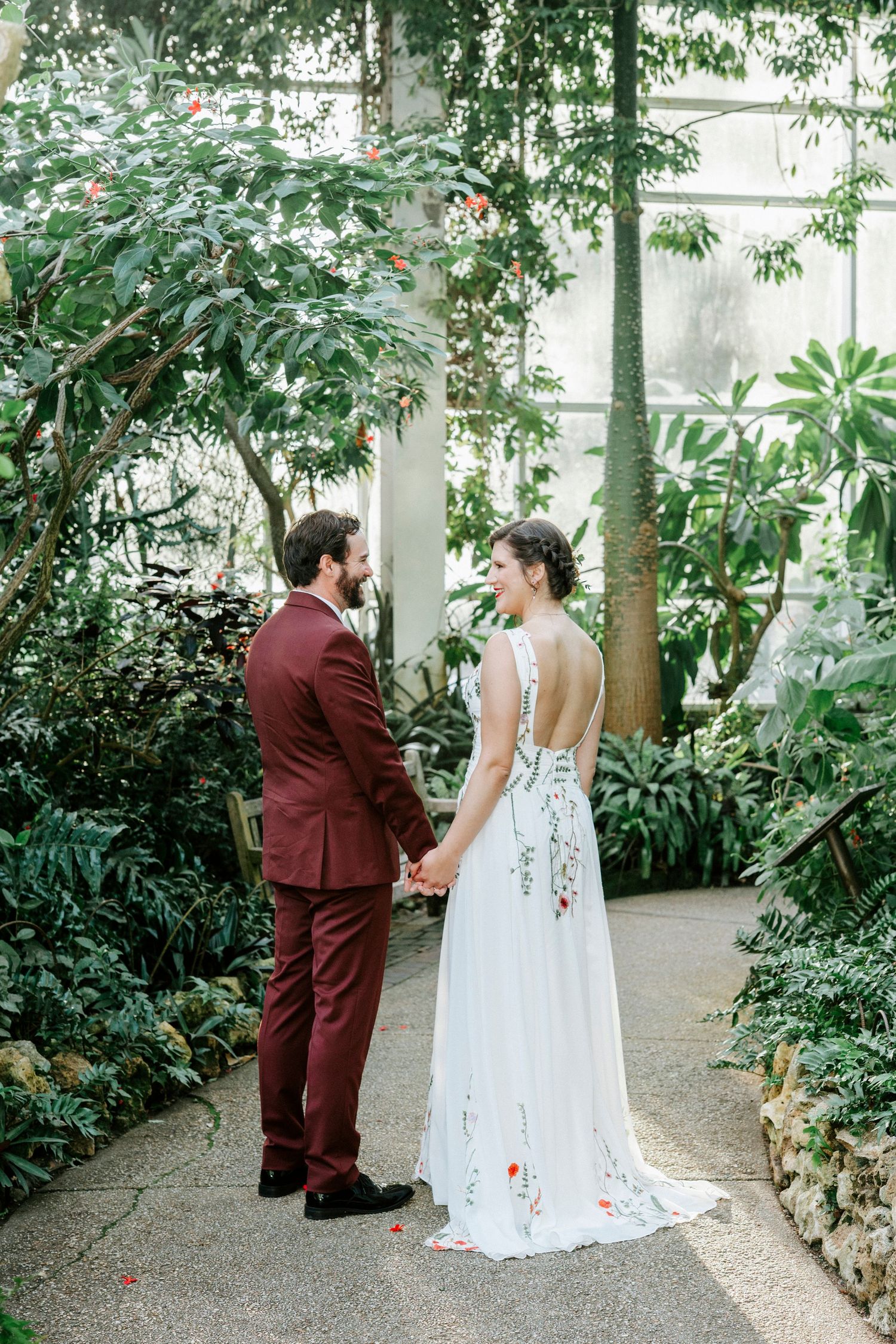 A couple sharing a private moment in a lush greenhouse setting during their wedding.