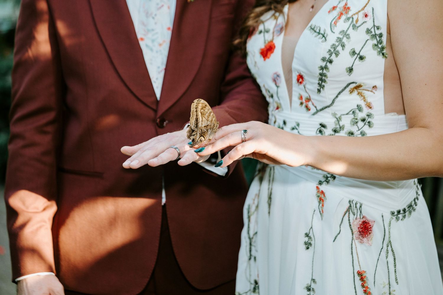 Close-up shot of arms showing floral dress detail next to burgundy suit jacket.