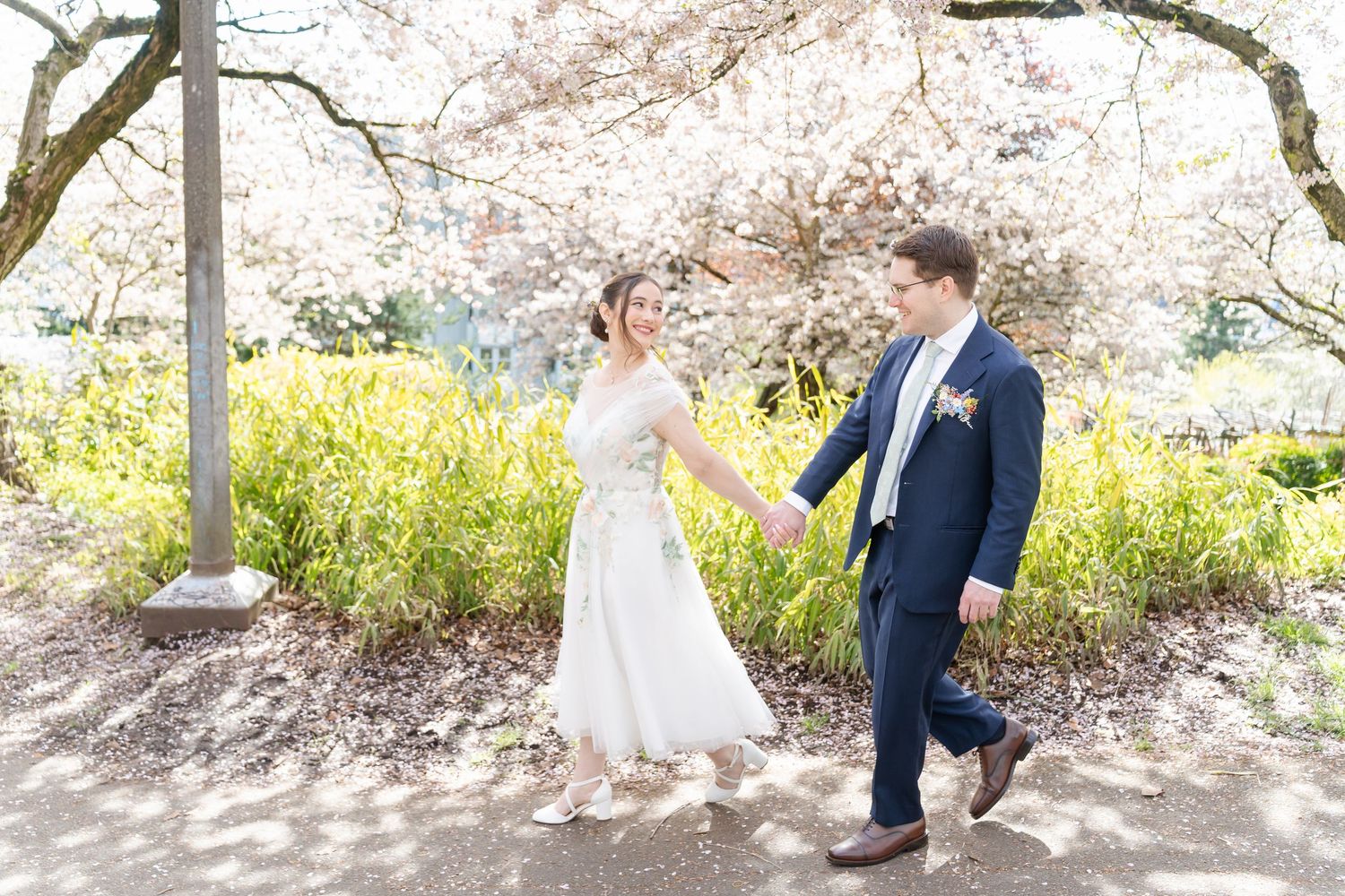 Romantic spring wedding photos under blooming cherry blossom trees in a serene garden setting.