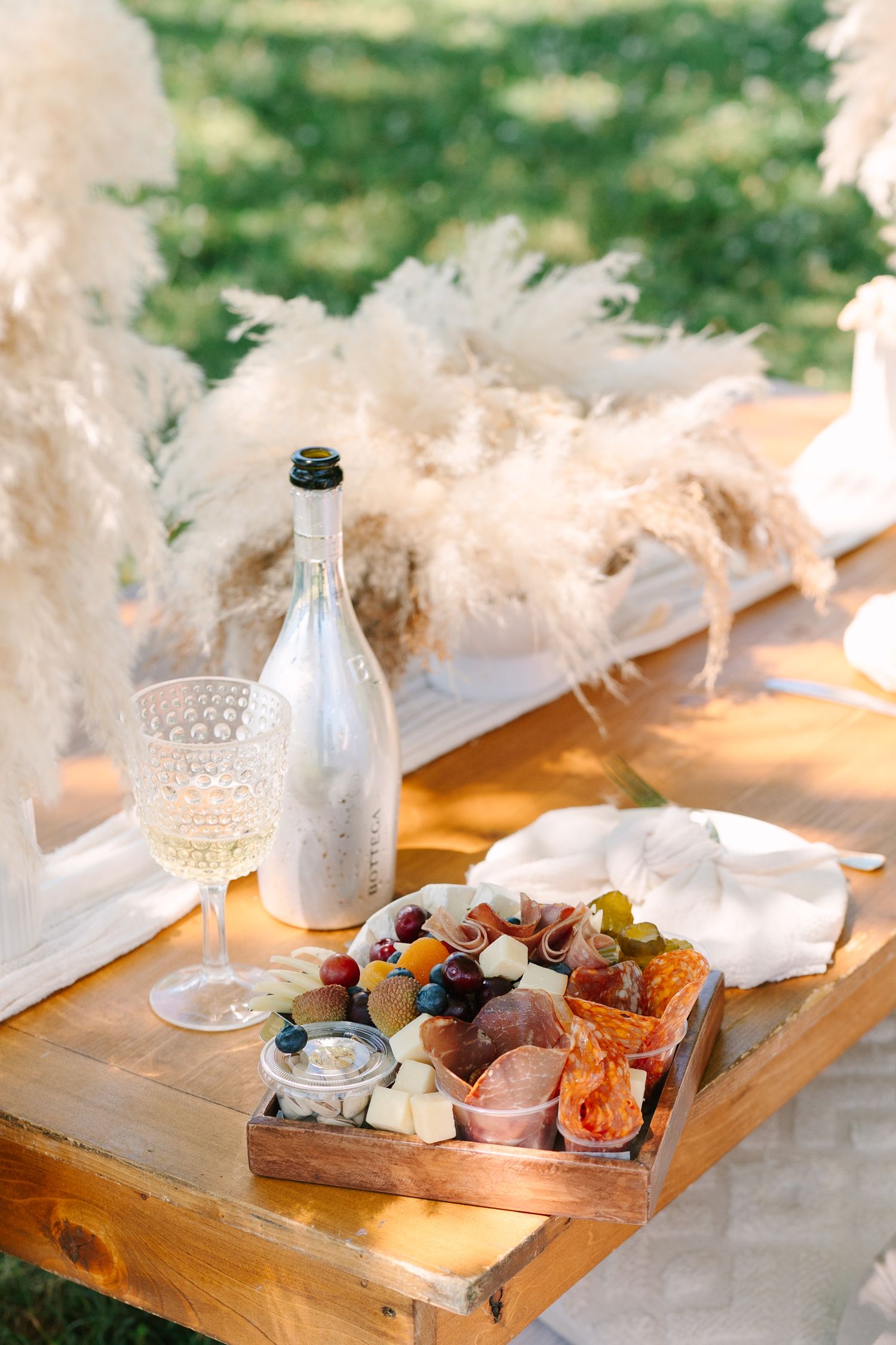 Elegant wooden charcuterie board with cheese, fruits and wine setup for romantic dining.