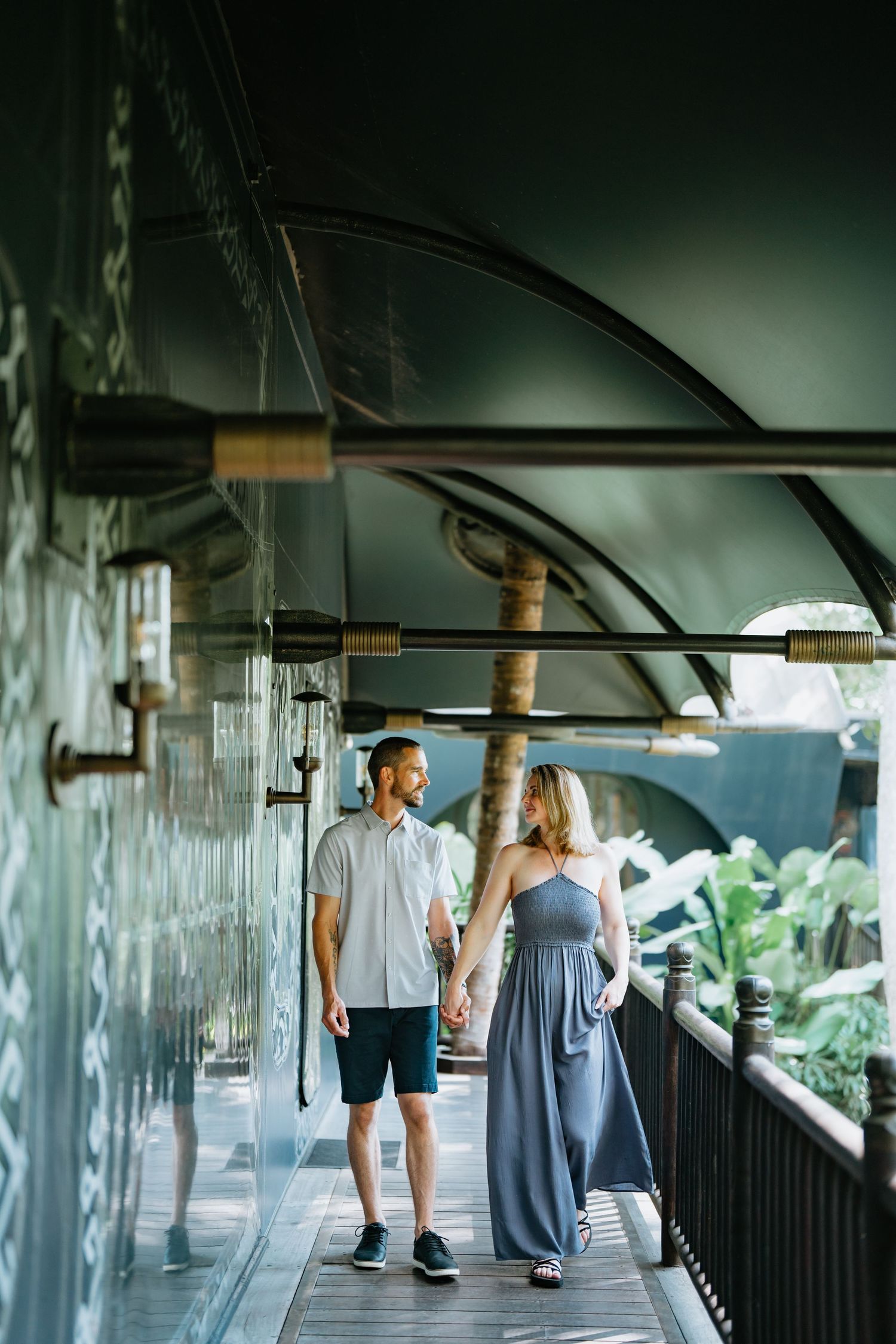 Two people stand in an indoor corridor with modern architectural details.