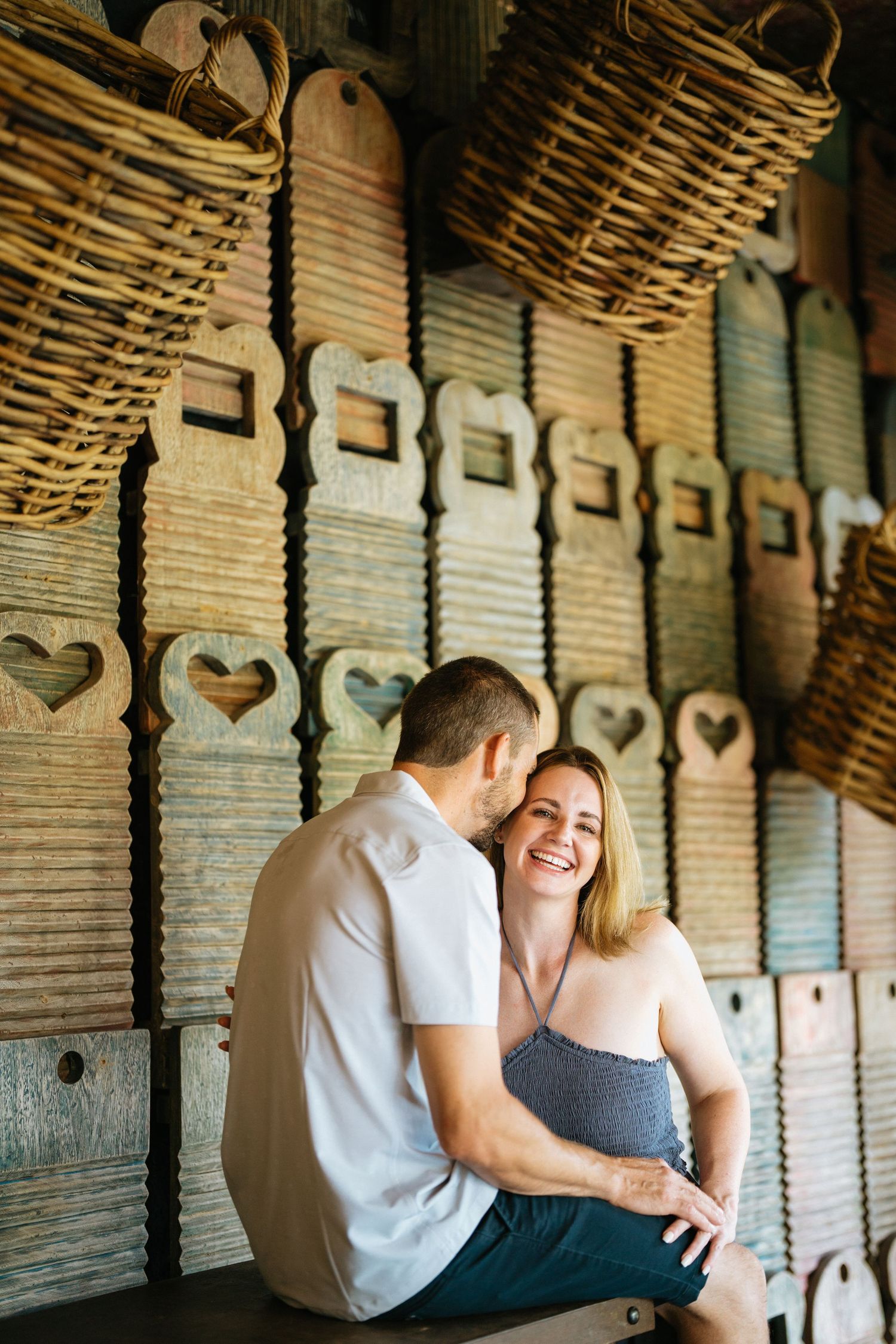 A couple shares a laugh while sitting in a rustic indoor setting with woven basket decor.