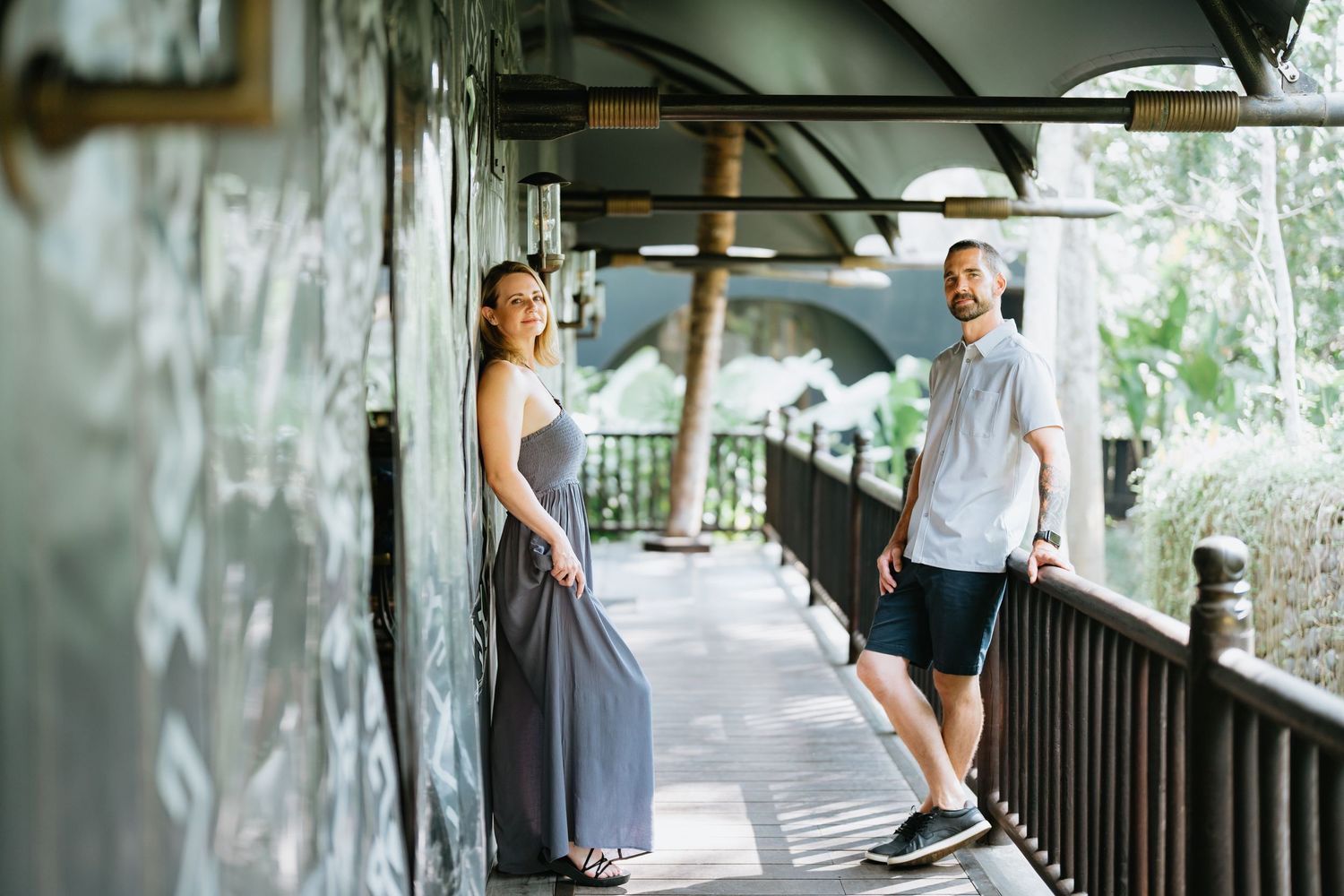 Covered walkway with wooden railings surrounded by tropical foliage.