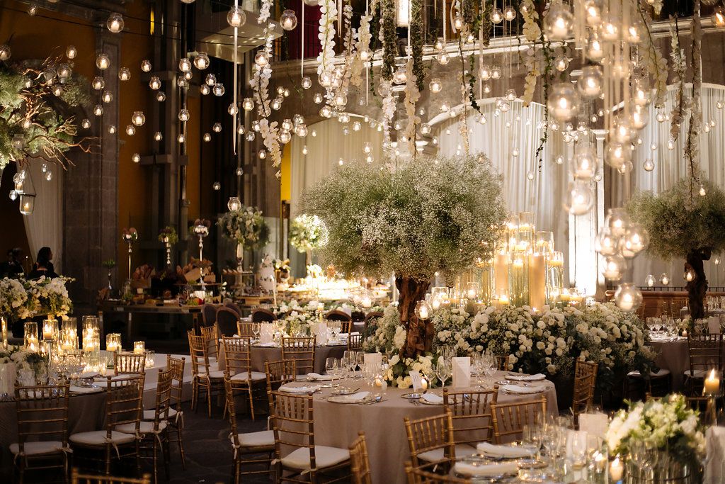 Luxurious wedding reception venue decorated with hanging lights and lush greenery creating a magical atmosphere.