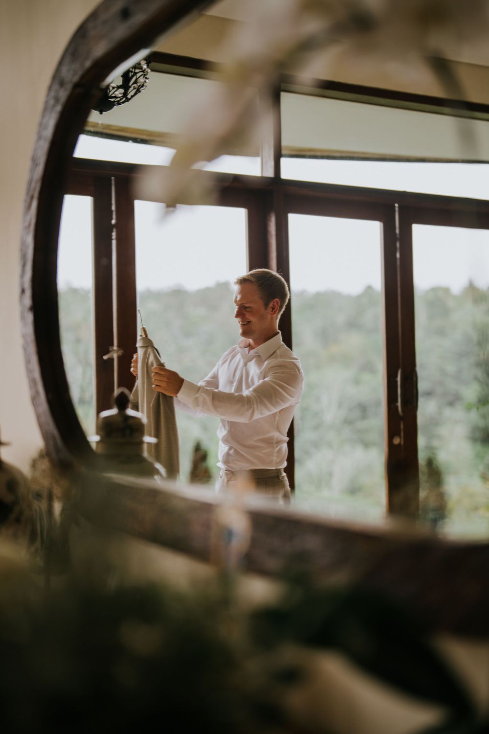 Sunlit room with wooden beams and windows showing someone in white preparing for an event.