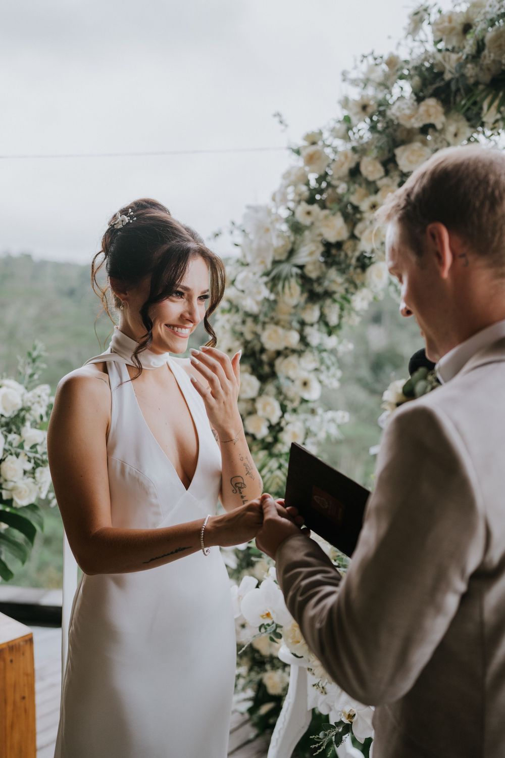 Emotional wedding ceremony moment under floral arch with white orchid decorations.