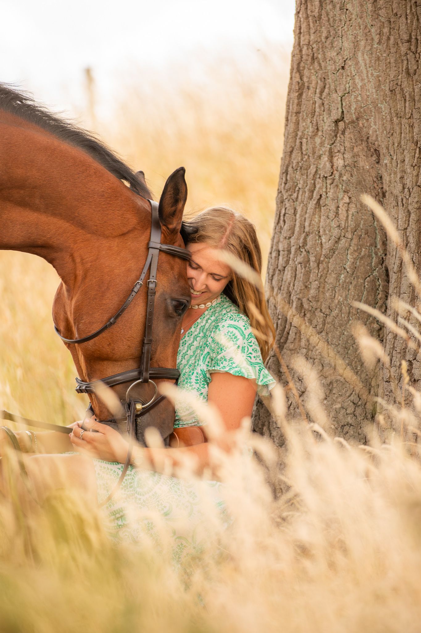 Young equestrian poses with palomino pony in a series of natural outdoor portraits showing their special bond.