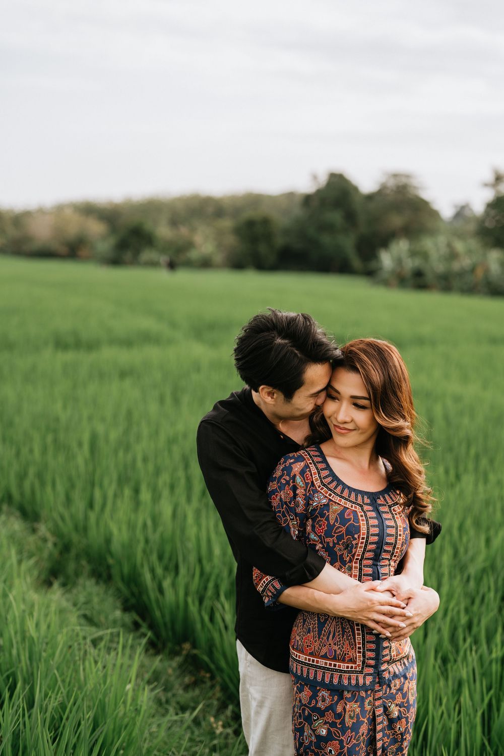 A tender embrace captured in a lush green field during golden hour.