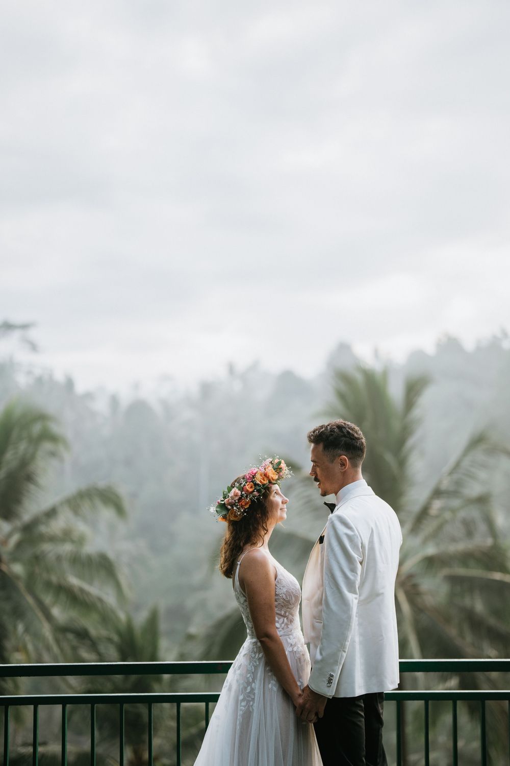 Couple sharing a romantic moment on a balcony overlooking misty tropical mountains.