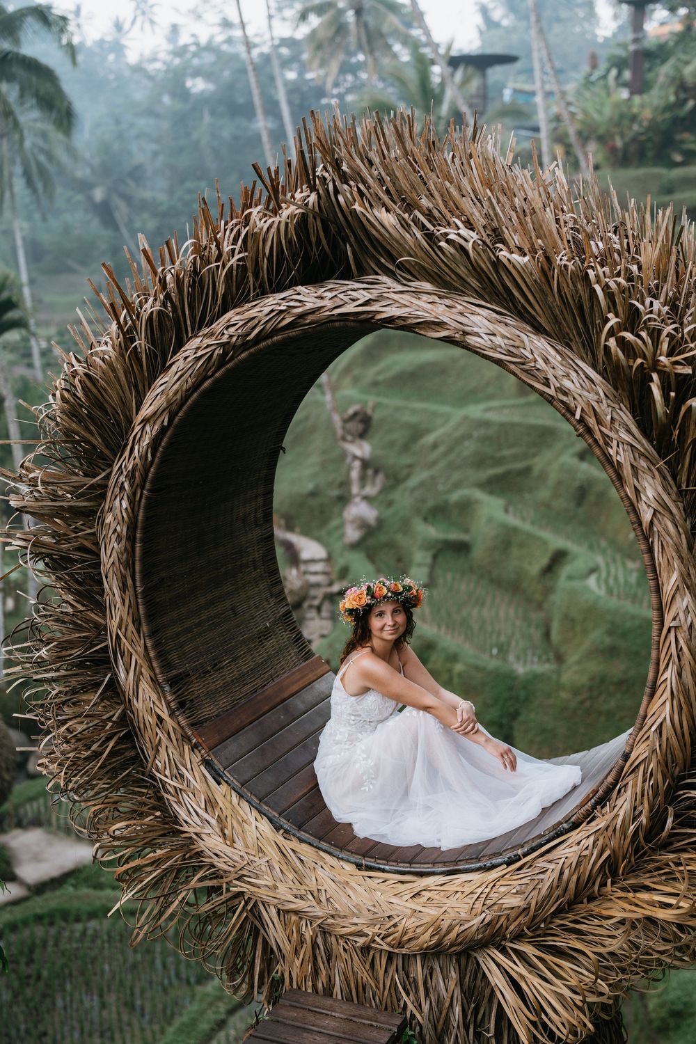 Wedding photo in a giant woven nest overlooking terraced rice fields and tropical landscape.